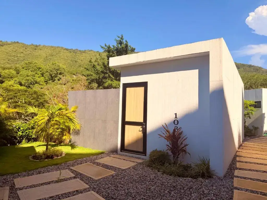 Camino de piedra entre plantas que llega a la puerta de una unidad del glamping