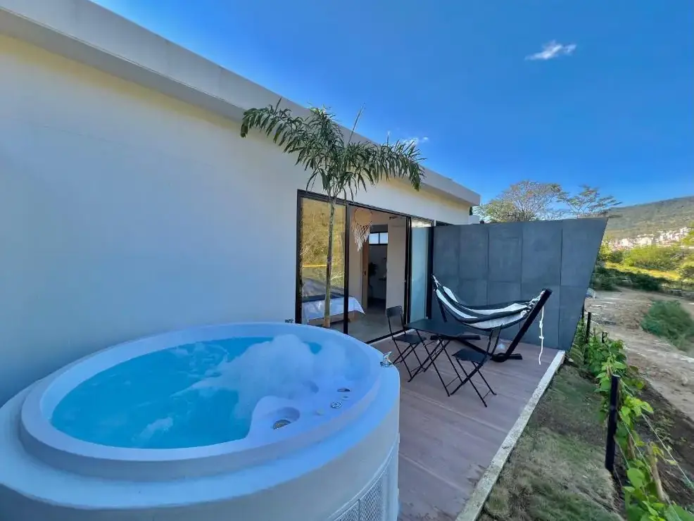Jacuzzi lleno en la terraza de madera de una unidad del glamping, con la montaña detrás