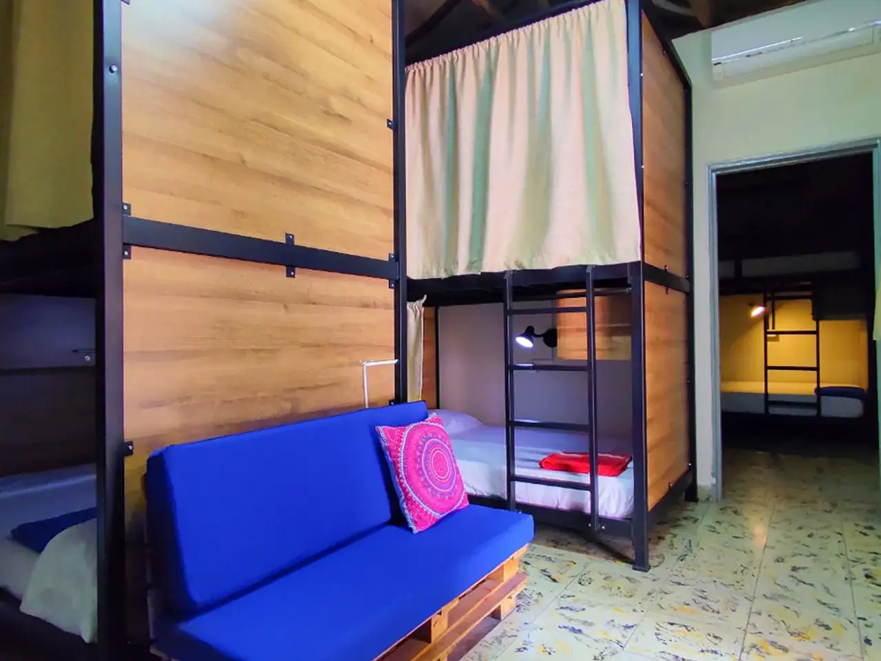 Dormitorio de 8 camas de Origen con camarotes de madera y sofá azul