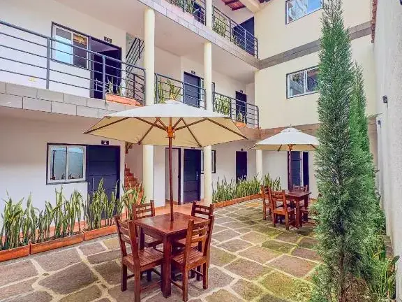 Patio interior de Origen con mesas de madera, parasoles blancos y plantas junto a los pasillos