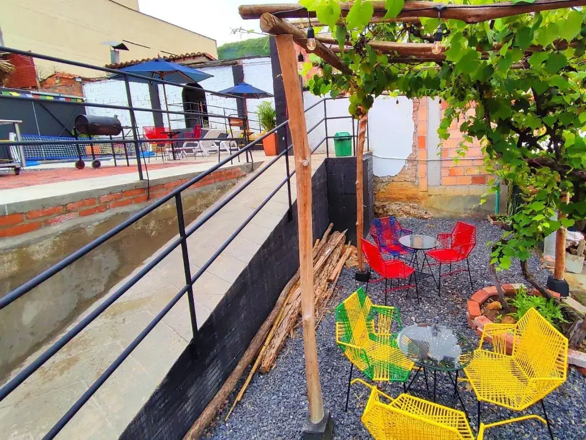 Terraza de Origen con sillas tejidas amarillas y rojas bajo una enredadera