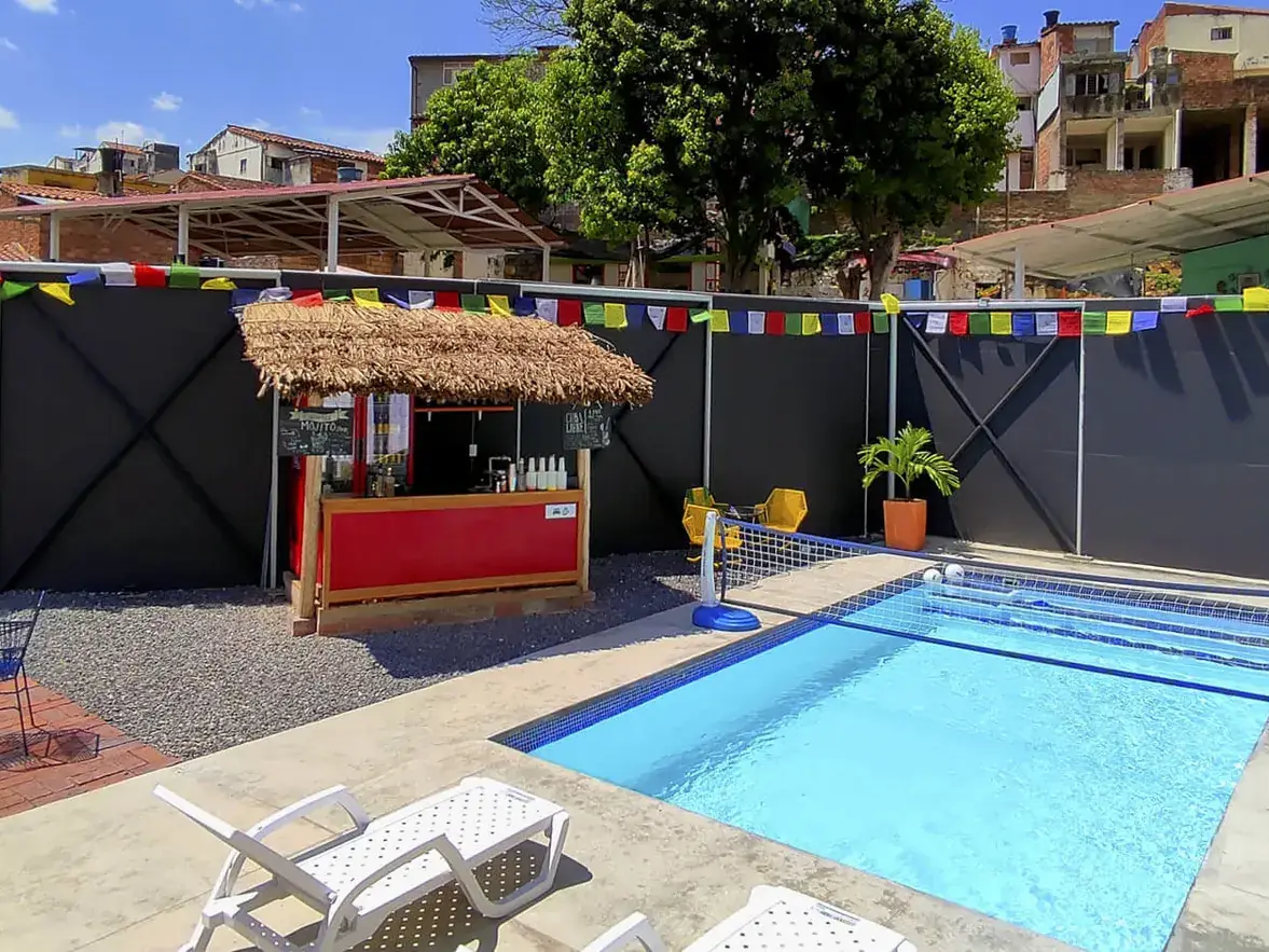 Zona de piscina de Origen con tumbonas blancas, bar de palma y banderines de colores