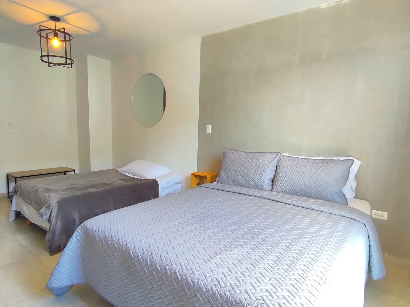 Cama queen tendida y sofá cama en el cuarto con cocina de Del Río