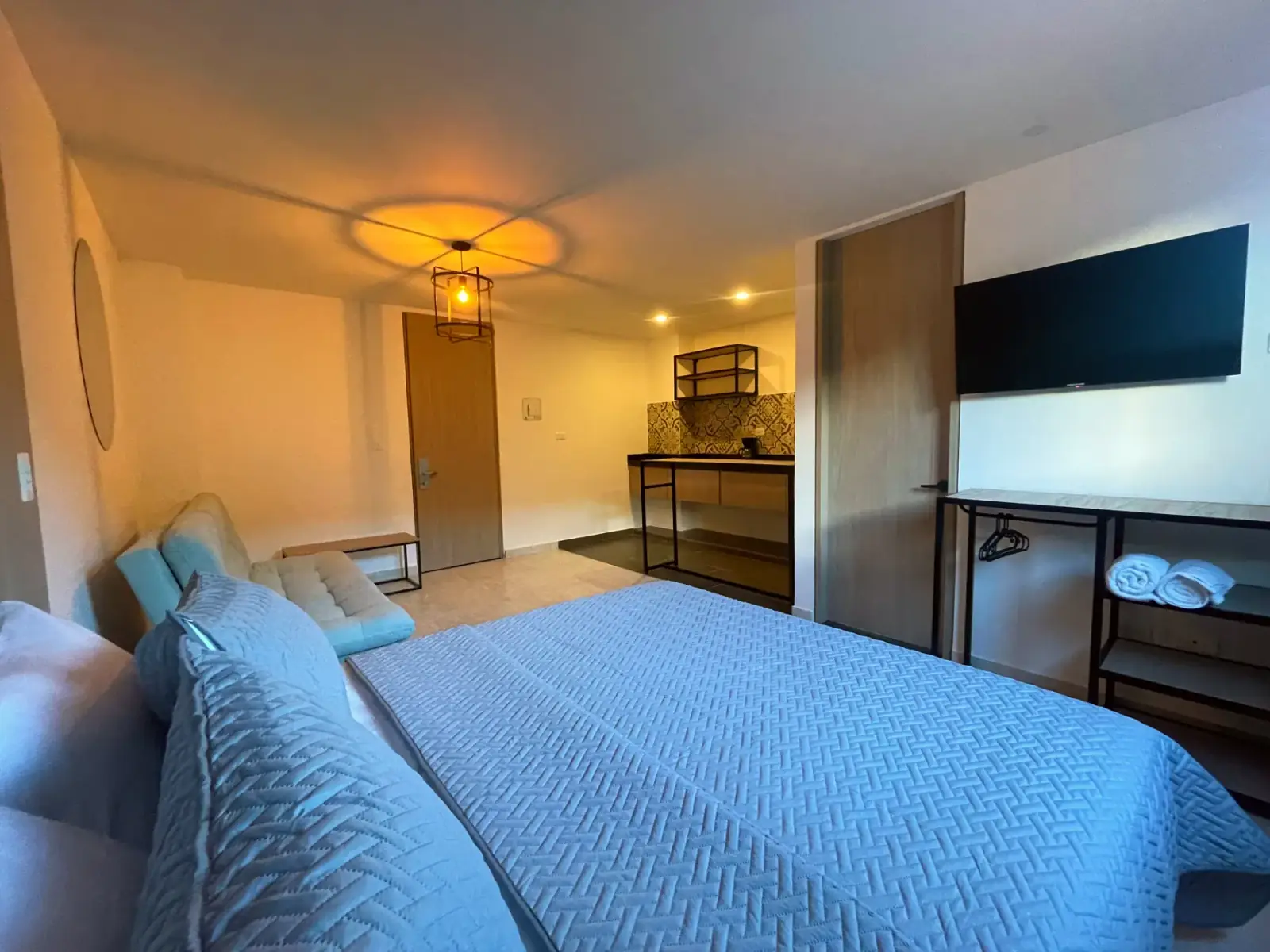 Cuarto con cocina en Del Río: sofá y televisor delante de la cama, y la cocina al fondo