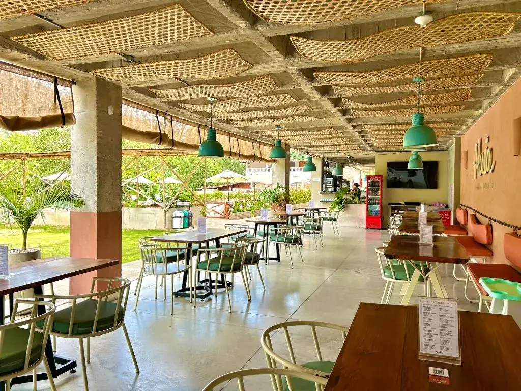 Interior de Alaia, el restaurante de Del Río: mesas de madera y lámparas verdes que cuelgan de un techo tejido